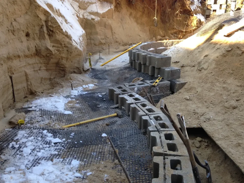 Construction site with cinder blocks partially covered with snow and reinforcement mesh visible.