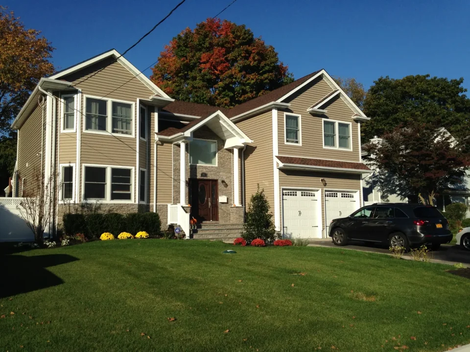 Two-story suburban house with beige siding, white trim, and a green lawn.