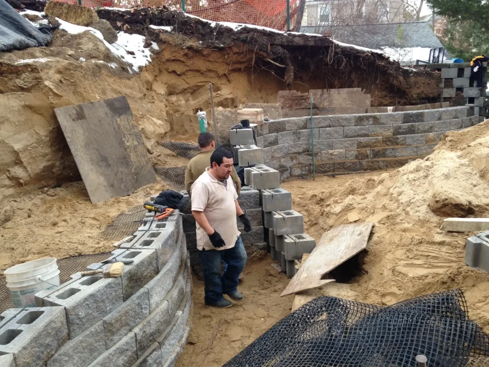 Construction site with retaining wall blocks and excavation work in progress.