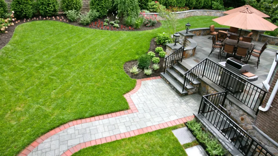 Landscaped backyard with patio furniture, stone walkways, and vibrant garden.