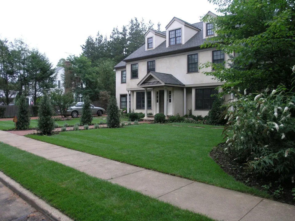 A two-story suburban home with a well-kept lawn and a car in the driveway.