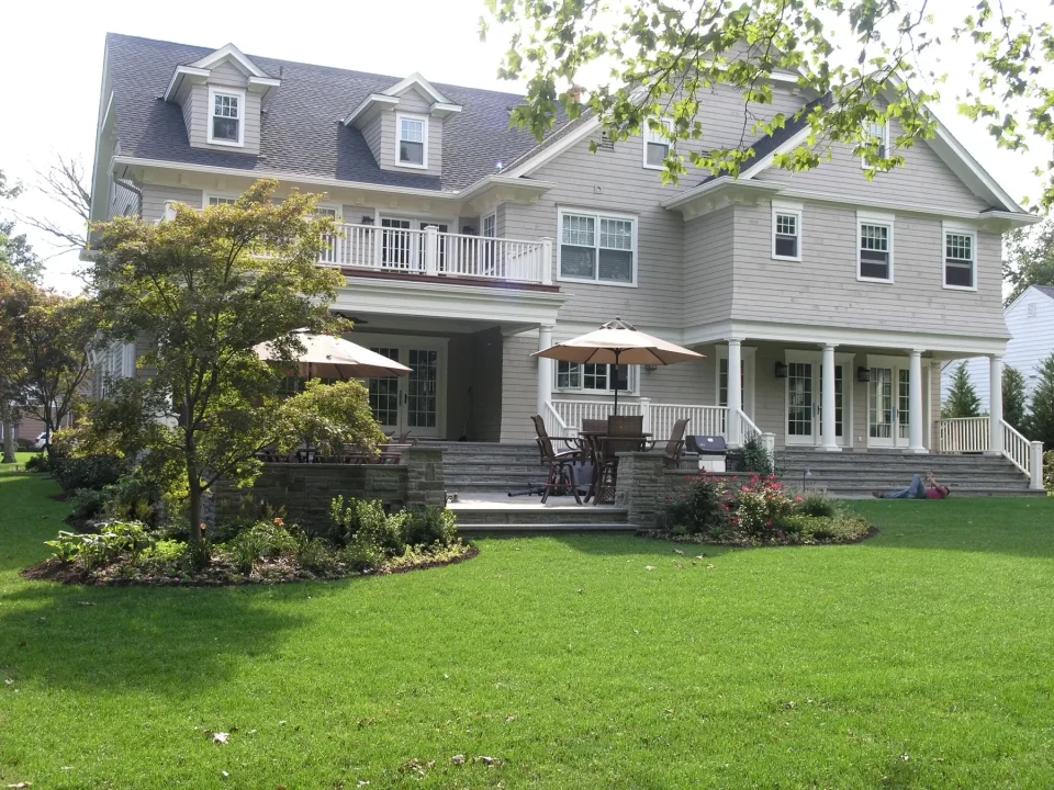 Two-story house with a porch, balcony, and landscaped lawn.
