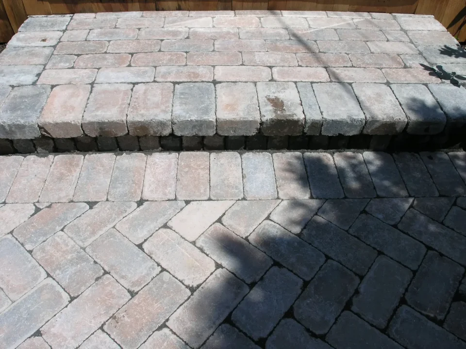 Brick paver patterns on a patio with shadows cast by an unseen object.