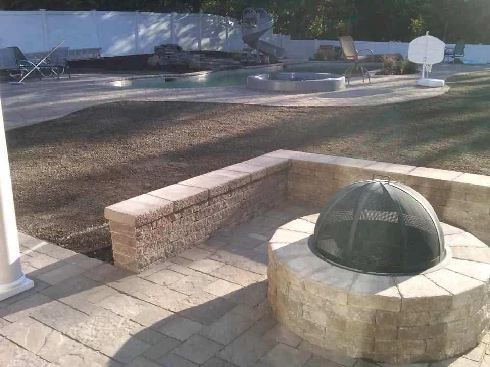 Backyard with a fire pit, swimming pool, sun loungers, and a basketball hoop.