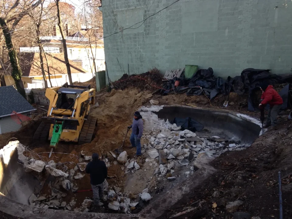 Workers and a bulldozer at a construction site with a partially demolished concrete structure.