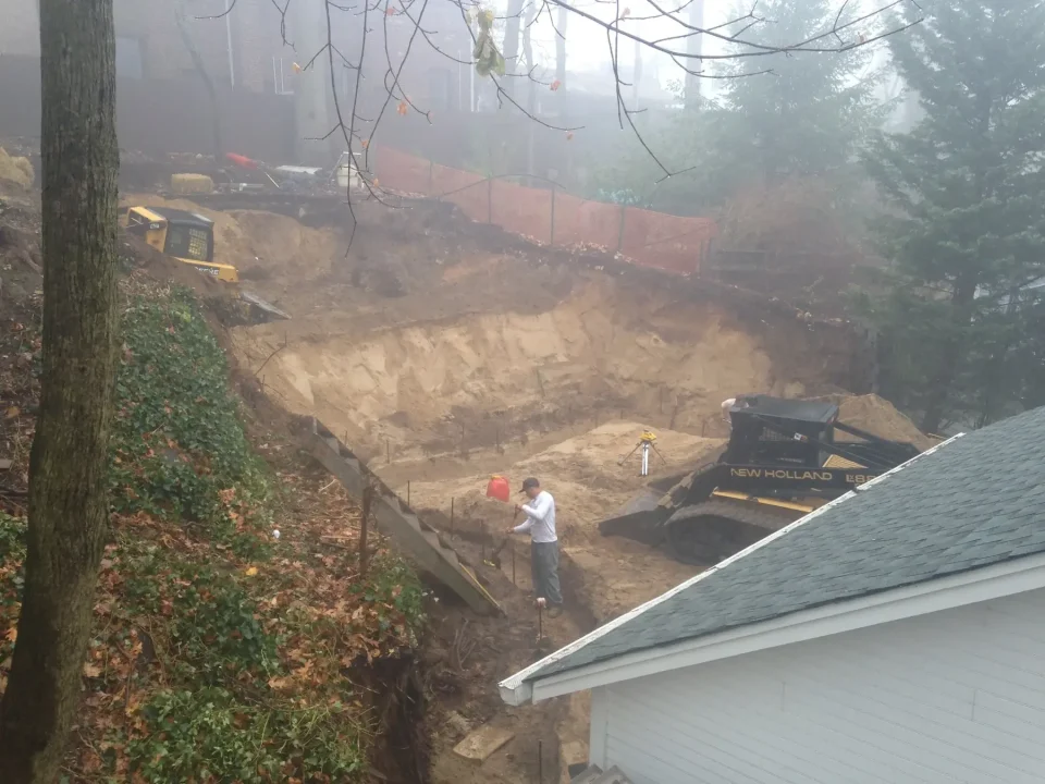 Construction site with excavation machinery and person in foggy weather.