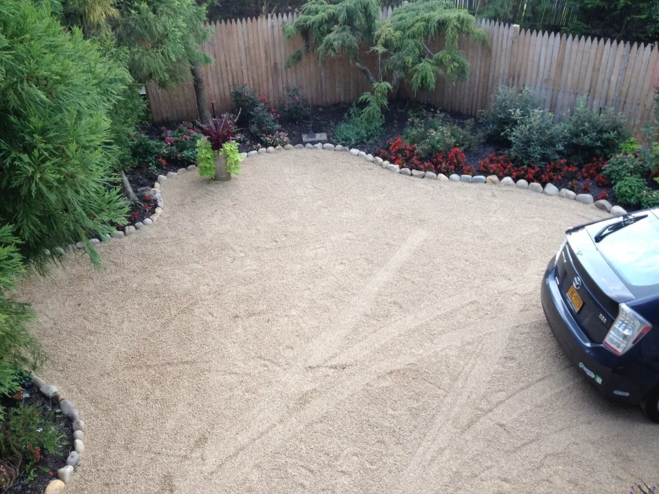 Well-manicured garden with a gravel driveway and a partial view of a car.