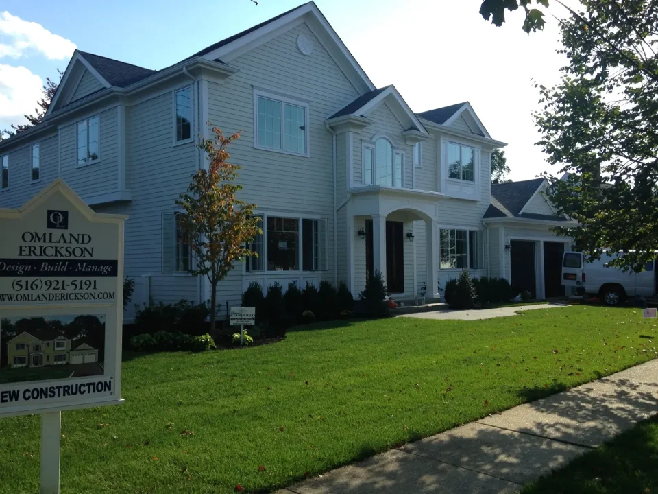 Two-story white house with columns, front lawn, and a construction sign.