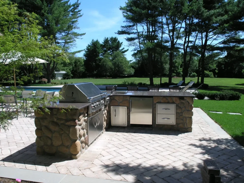 Outdoor stone kitchen with grill and green lawn background