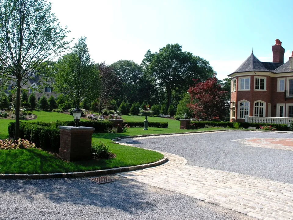 Elegant brick house with landscaped garden and cobblestone driveway.