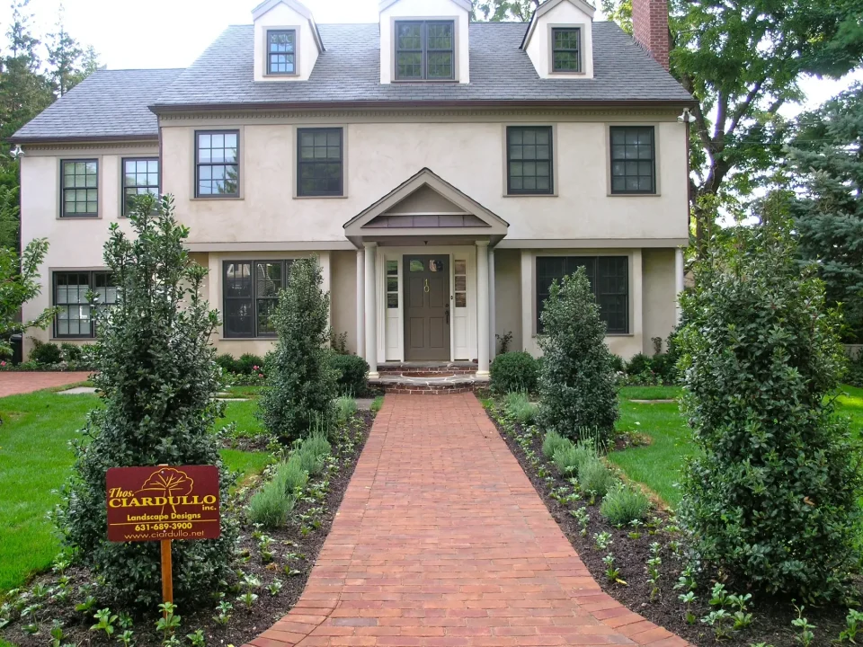 Beige two-story house with a red brick walkway, landscaping, and a Ciardullo sign on lawn.