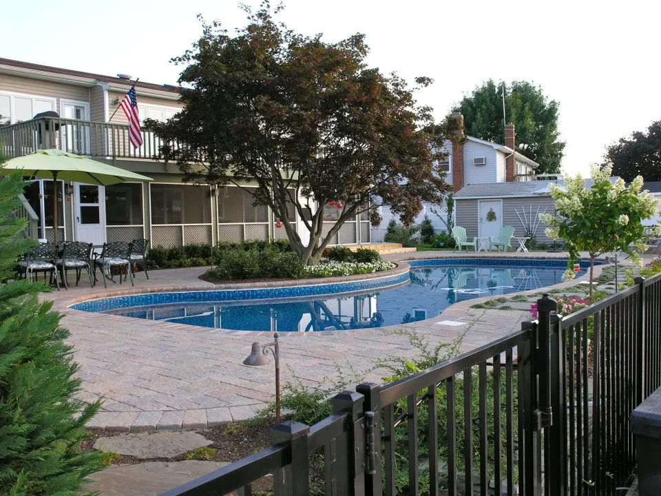 Backyard with a blue pool, patio area, and a house with the American flag.