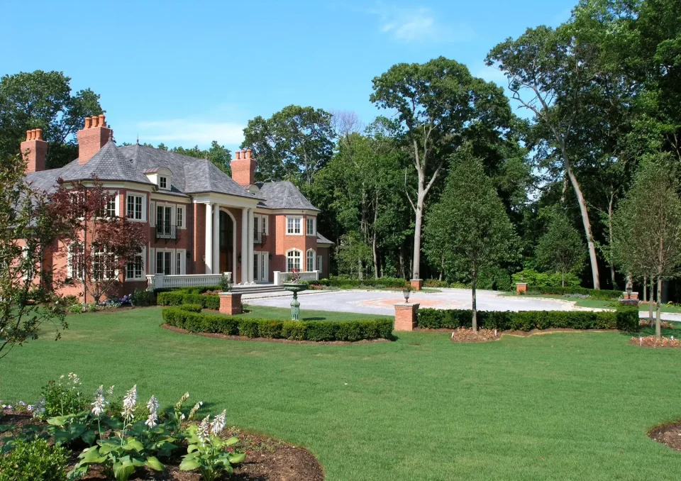 Elegant brick mansion with columns and landscaped garden.