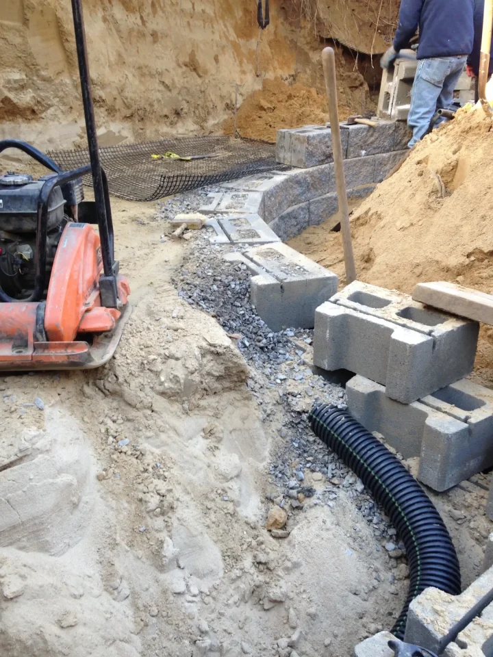 Construction site with unfinished masonry, excavation, and a worker.