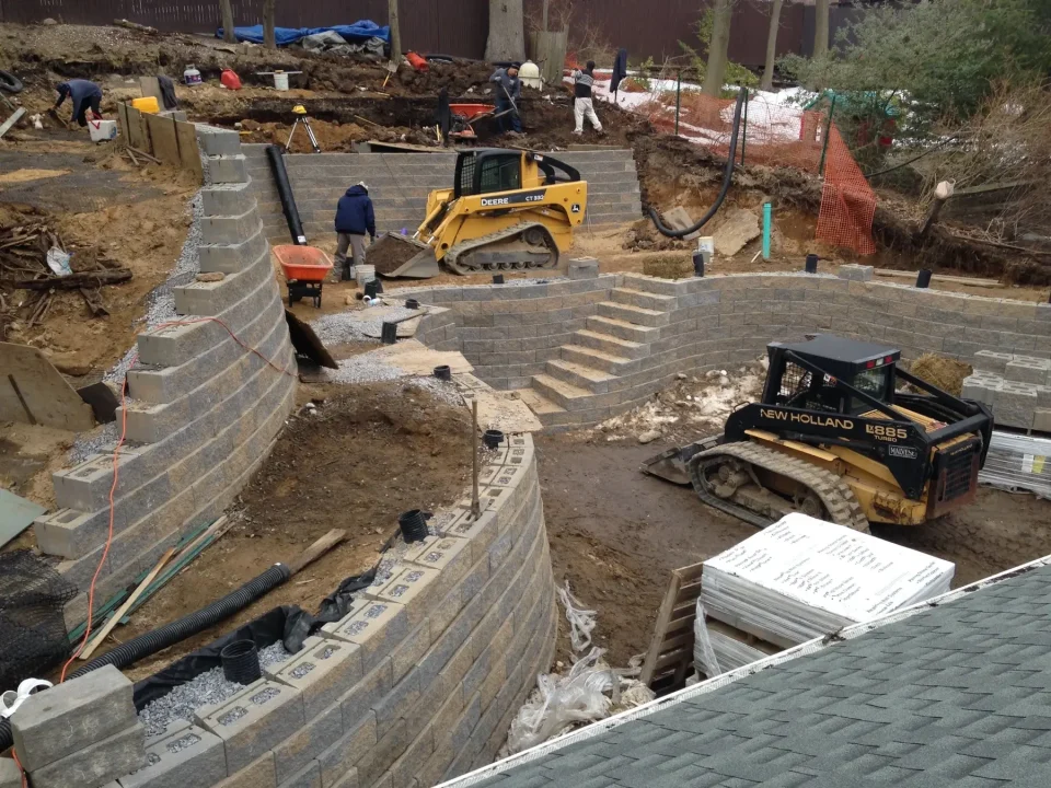 Active construction site with excavators, retaining walls, and workers.