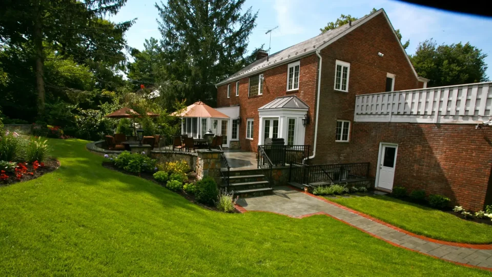 Brick house with a well-manicured lawn and patio area with umbrellas.