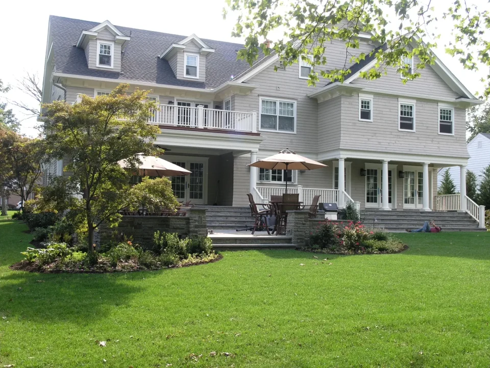 Two-story house with balcony, patio area, and landscaped garden.