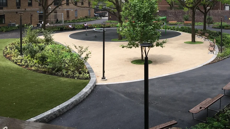 Urban park with curved paths, benches, lush greenery, and a playground.